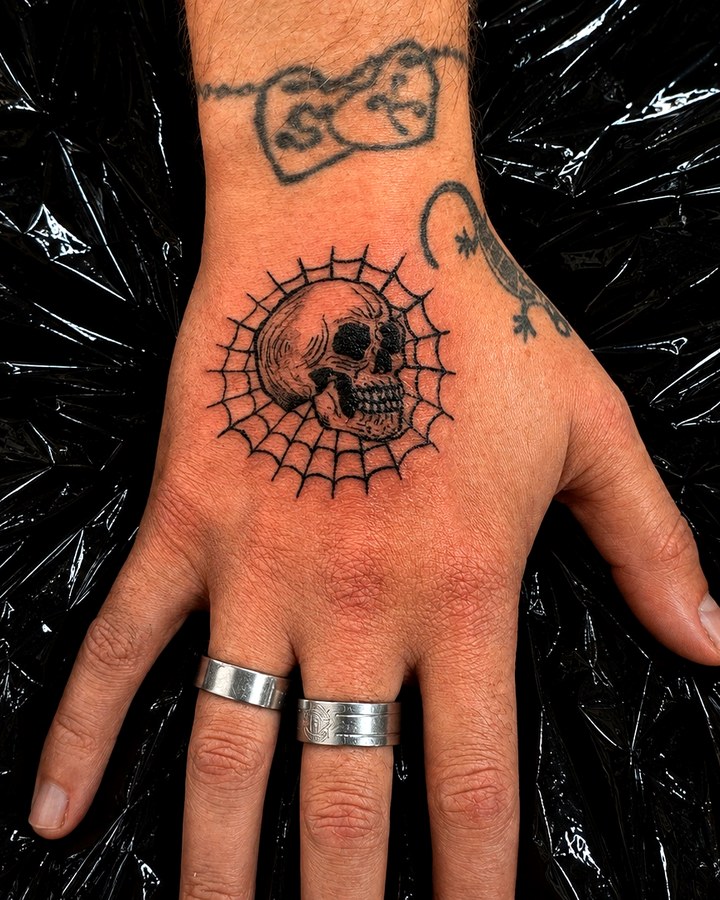Small skull and web tattoo on hand